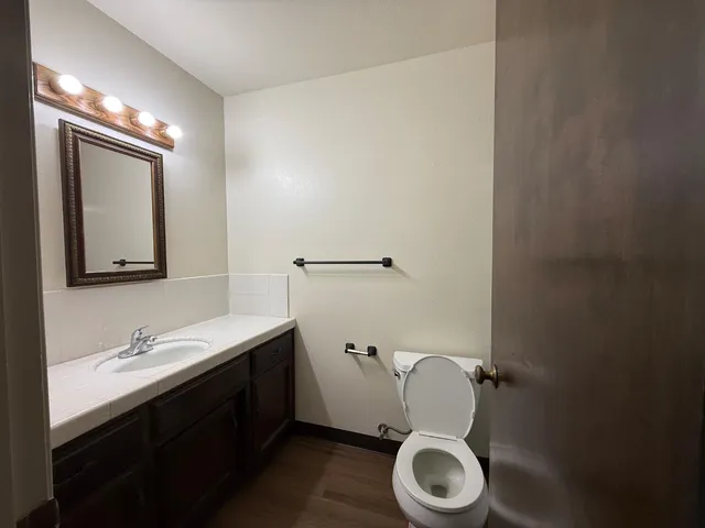 a bathroom with a granite countertop toilet sink and mirror