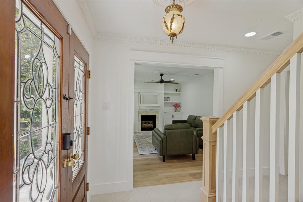 4316 Springbranch Drive Benbrook, TX 76116 - Photo 6 of 39 Entryway featuring stained glass double doors with brass hardware, a detailed ceiling medallion with an ornate fixture, and a staircase with a natural wood handrail and white balusters