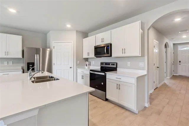 a kitchen with a sink a stove a refrigerator a center island and cabinets