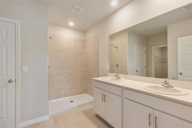 a bathroom with a double vanity sink toilet mirror and shower