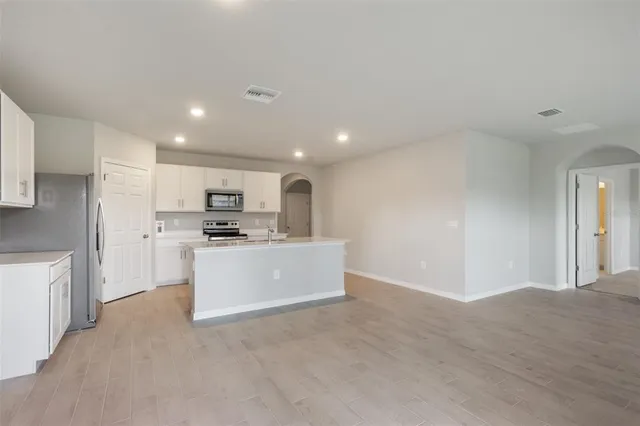 a view of kitchen with granite countertop refrigerator and white cabinets