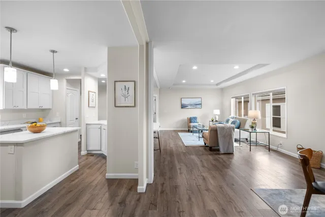 a living room with stainless steel appliances dining table wooden floor and a window