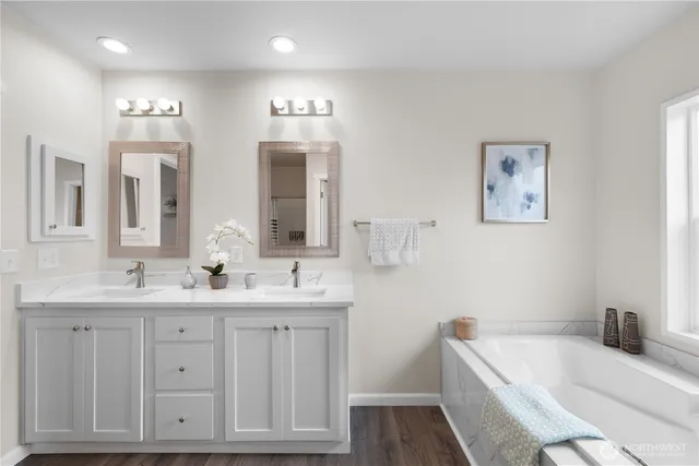 a bathroom with a tub a sink and mirror