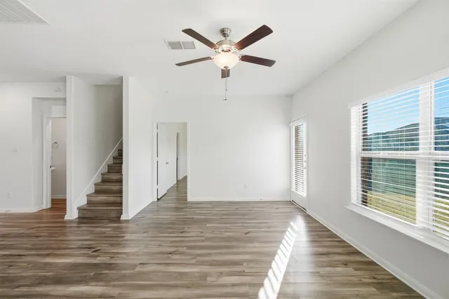a view of empty room with wooden floor and ceiling fan