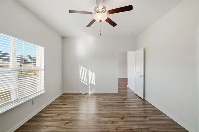 a view of an empty room with window and wooden floor