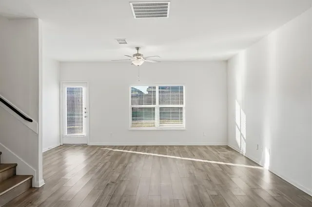an empty room with wooden floor and window