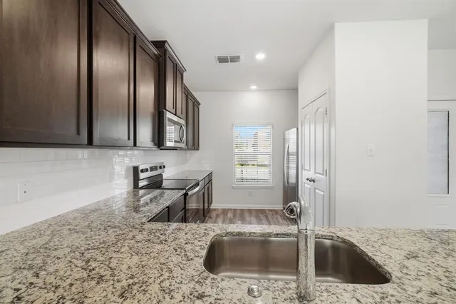 a kitchen with granite countertop a sink a stove and a microwave