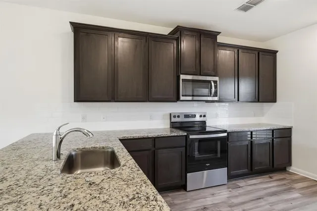 a kitchen with stainless steel appliances granite countertop a sink stove and microwave