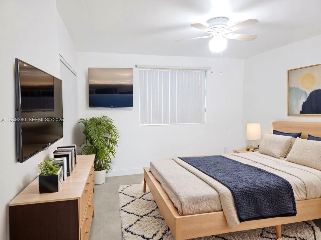 2620 South University Drive, Unit 111 Davie, FL 33328 - Photo 3 of 49 a bedroom with a bed potted plants on the dresser and a chandelier