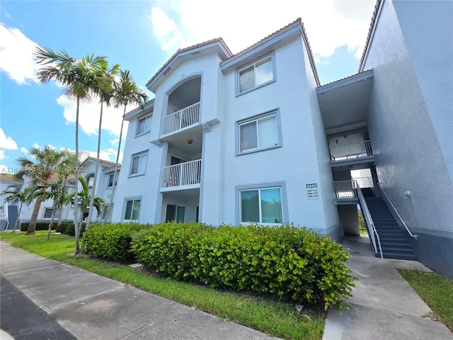 a front view of a multi story residential apartment building with yard and entertaining space