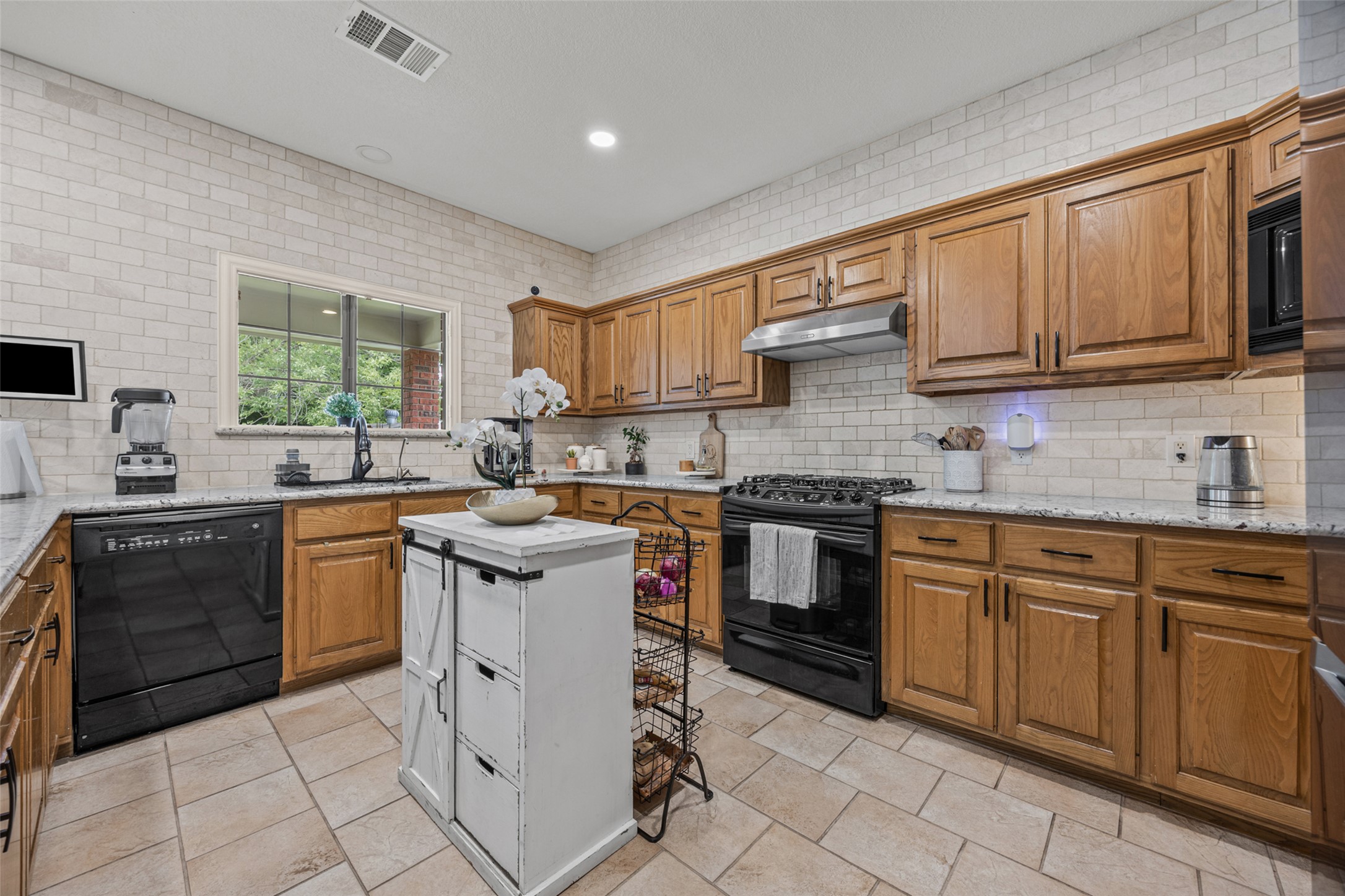 2000 Spinel Road Pflugerville, TX 78660 - Photo 8 of 31 Well-lit kitchen with granite counters, warm wood cabinetry, and a subway tile backsplash.