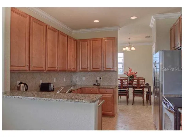 a kitchen with stainless steel appliances granite countertop a refrigerator a sink a stove and white cabinets with wooden floor