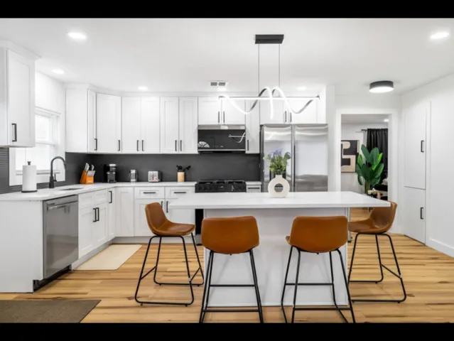a kitchen with stainless steel appliances kitchen island granite countertop a table chairs sink and cabinets