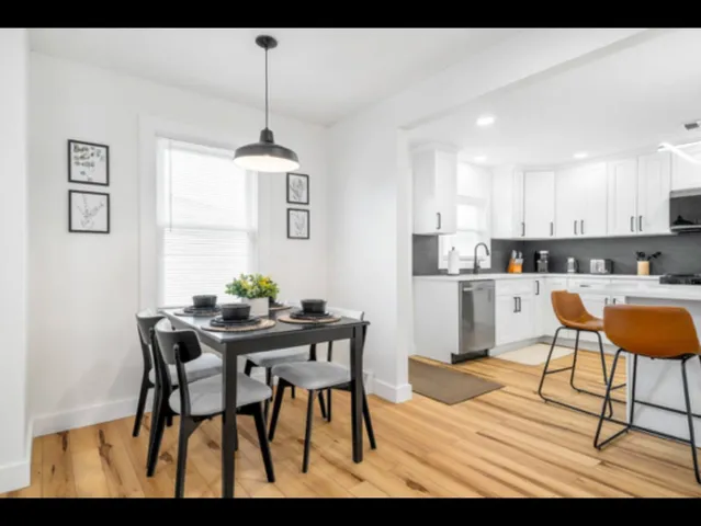 a kitchen with stainless steel appliances kitchen island granite countertop a dining table chairs and a refrigerator