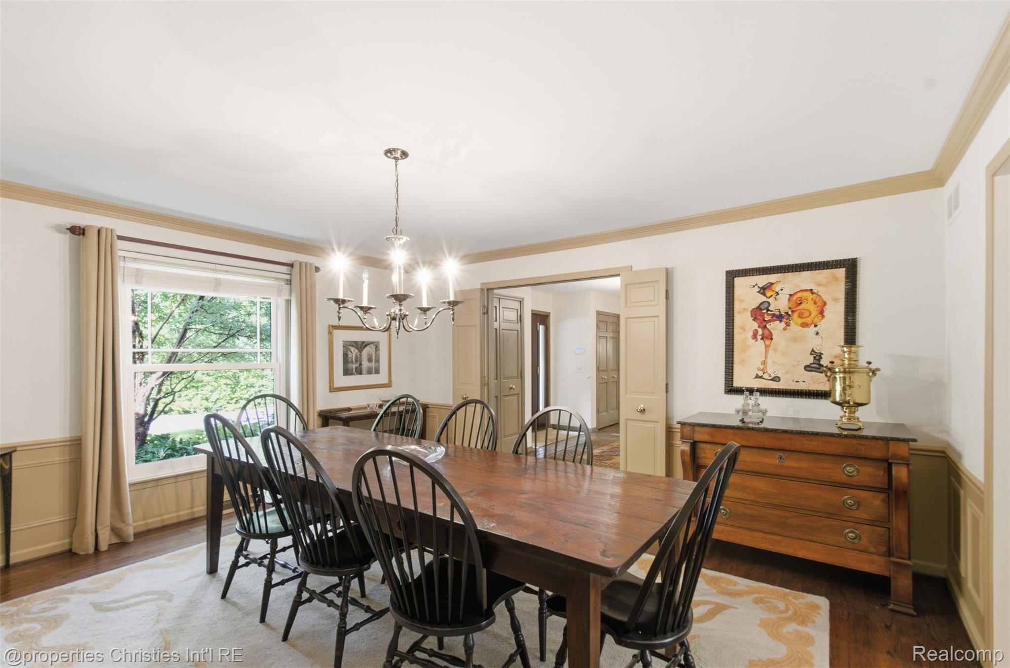 25235 Canterbury Road Franklin, MI 48025 - Photo 18 of 56 Formal dining area featuring hardwood flooring, a large window, crown molding, wainscoting, and a chandelier