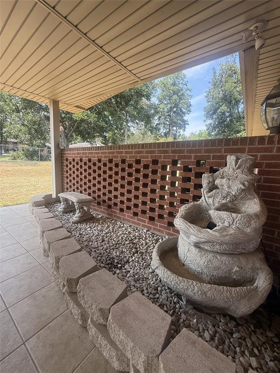 304 6th Street Northwest Springhill, LA 71075 - Photo 38 of 38 Covered patio featuring a brick wall with decorative openings, a stone-look water feature, and a stone-look bench