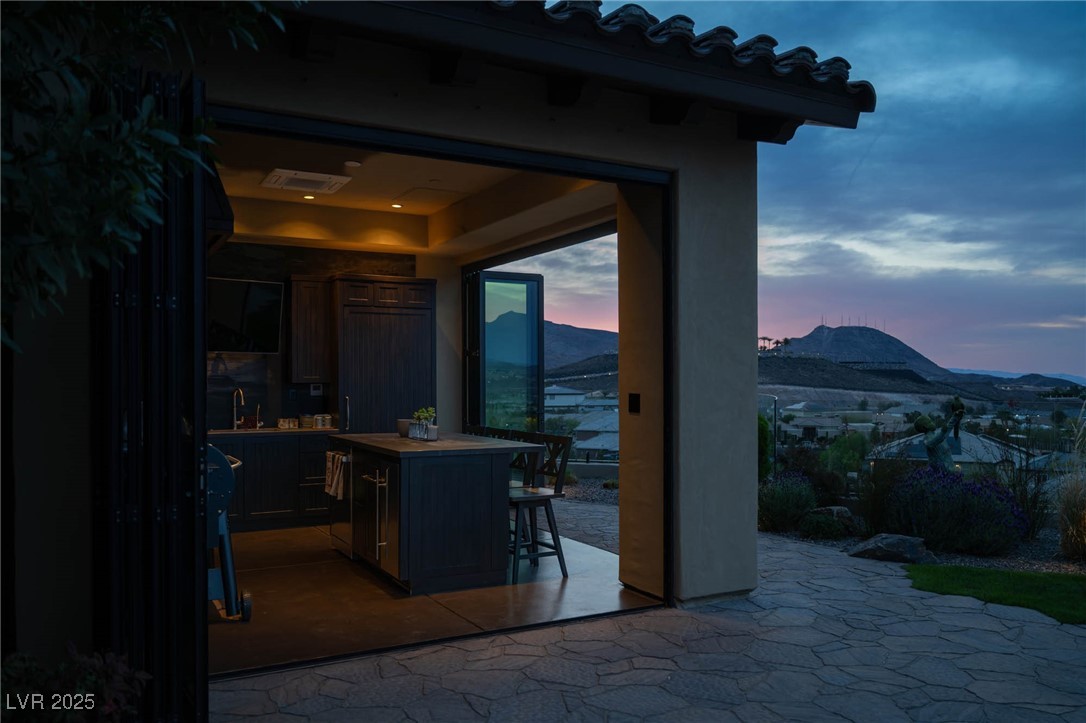 1123 Christian Road Henderson, NV 89002 - Photo 23 of 83 Outdoor kitchen at dusk with a mountain views, bifolding doors, pebble ice maker, griller, smoker, sub-zero panel front refrigerator, plus Mitsubishi heating and cooling