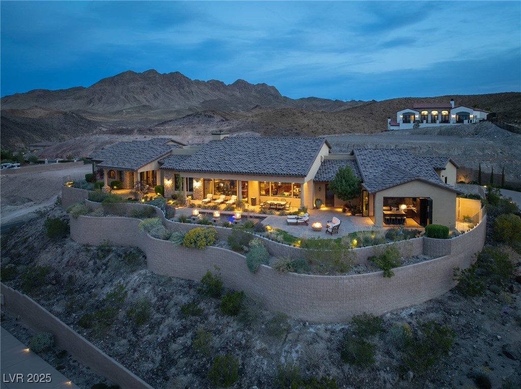 1123 Christian Road Henderson, NV 89002 - Photo 27 of 83 Rear view of property featuring a lit fireplace, a mountain view, stucco siding, and a patio area
