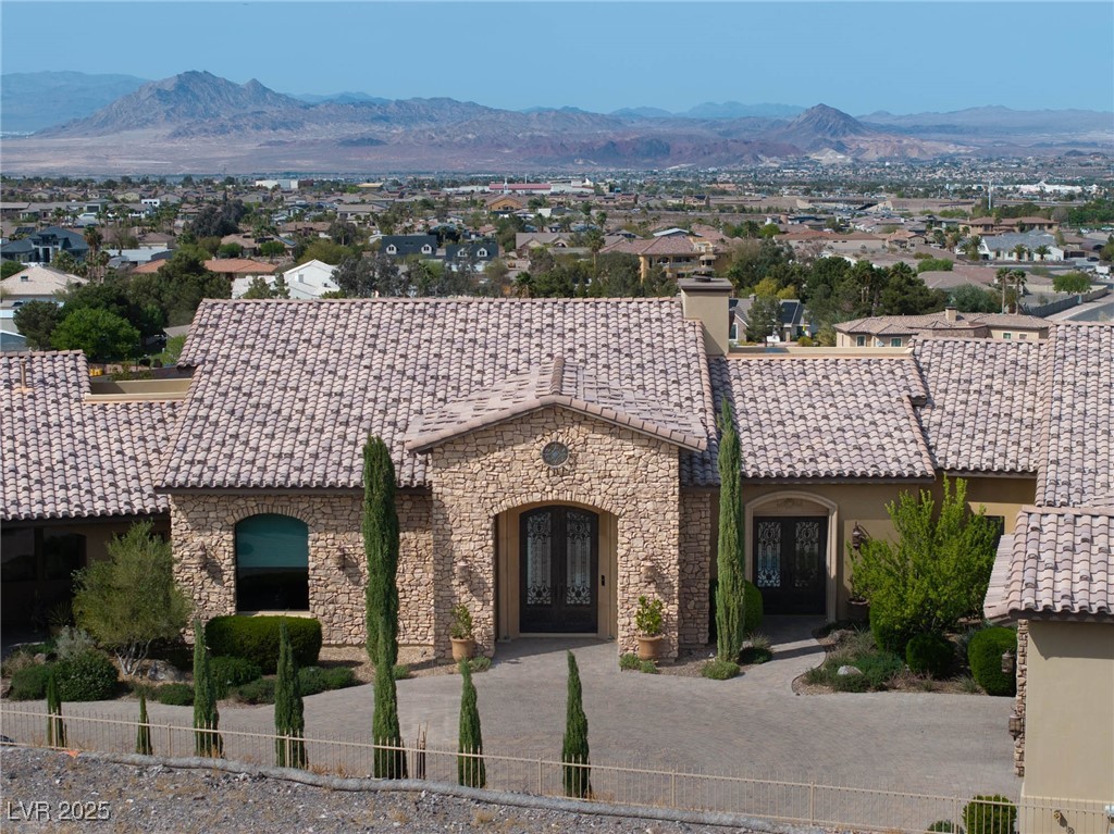 1123 Christian Road Henderson, NV 89002 - Photo 31 of 83 Property featuring iron doors, stone siding, a mountain views, and a chimney.
