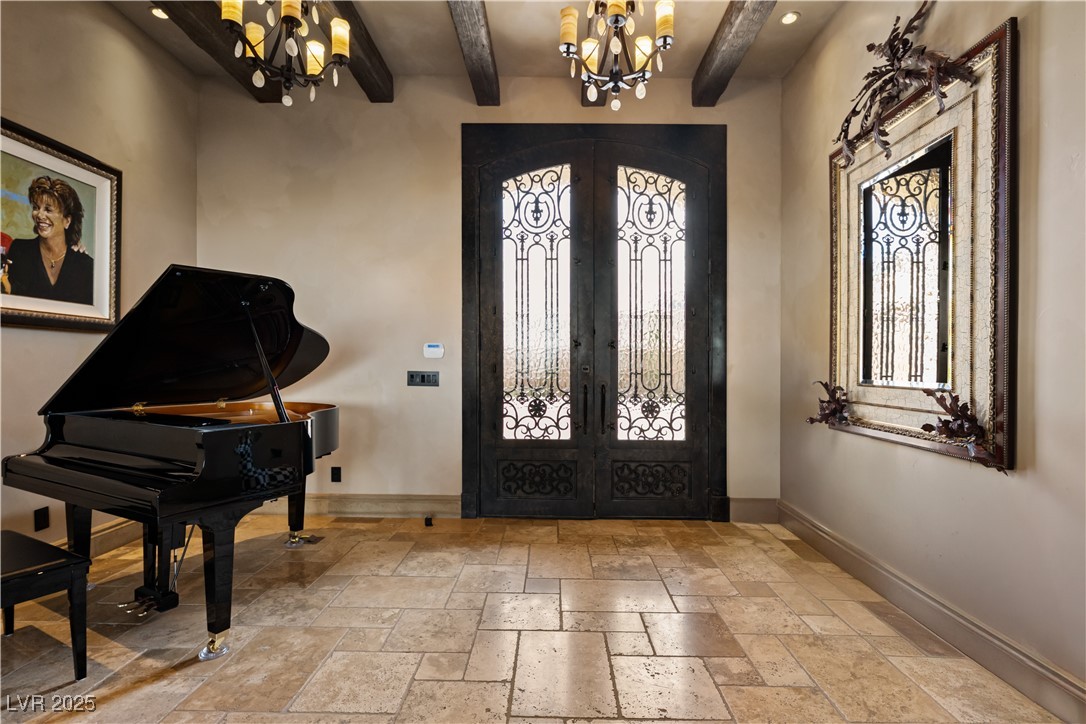 1123 Christian Road Henderson, NV 89002 - Photo 32 of 83 Entrance foyer with a notable chandelier, baseboards, iron doors, beam ceiling, and stone tile floors
