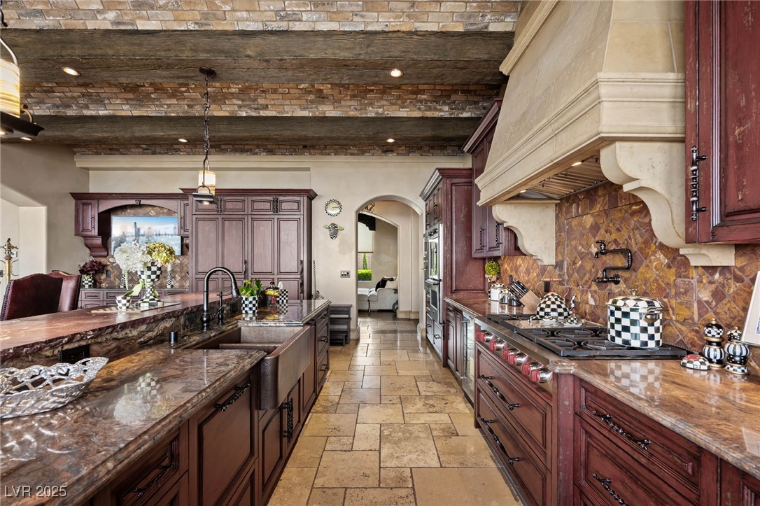1123 Christian Road Henderson, NV 89002 - Photo 42 of 83 Kitchen with arched walkways, a sink, custom range hood, backsplash, and stone tile flooring
