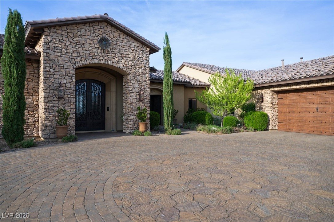 1123 Christian Road Henderson, NV 89002 - Photo 78 of 83 View of front of home with a tiled roof, stone siding, stucco siding, and curved driveway