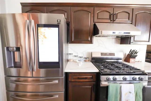 a kitchen with stainless steel appliances granite countertop a refrigerator and a stove