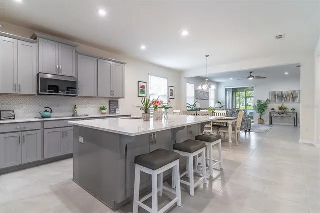 a kitchen with stainless steel appliances a sink a stove a refrigerator cabinets and chairs