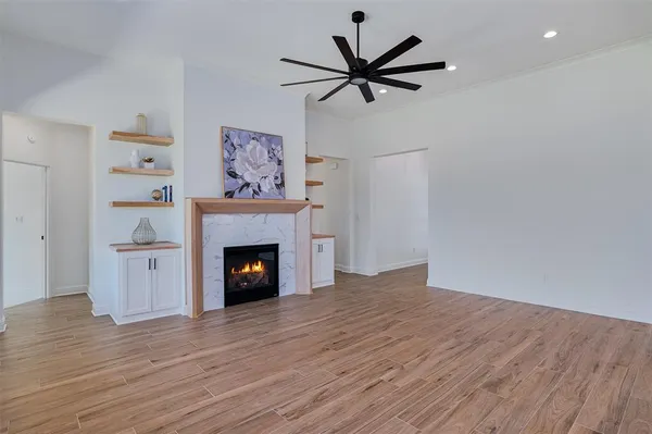 a view of a livingroom with a fireplace a ceiling fan and windows