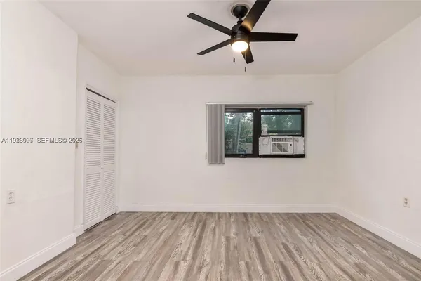 an empty room with wooden floor fan and windows