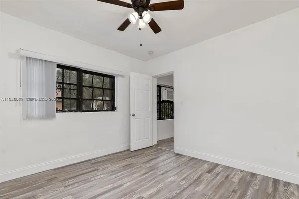 a view of an empty room with a window and wooden floor