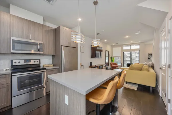 a large kitchen with kitchen island a stove a sink a refrigerator and a dining table with wooden floor