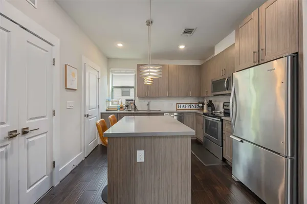 a kitchen with kitchen island a refrigerator a sink and wooden floor