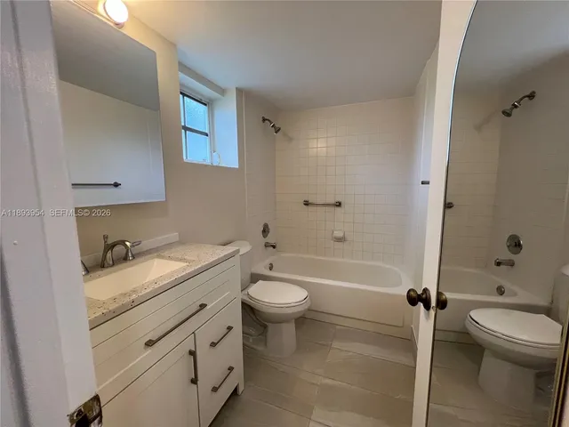 a bathroom with a granite countertop toilet sink and mirror