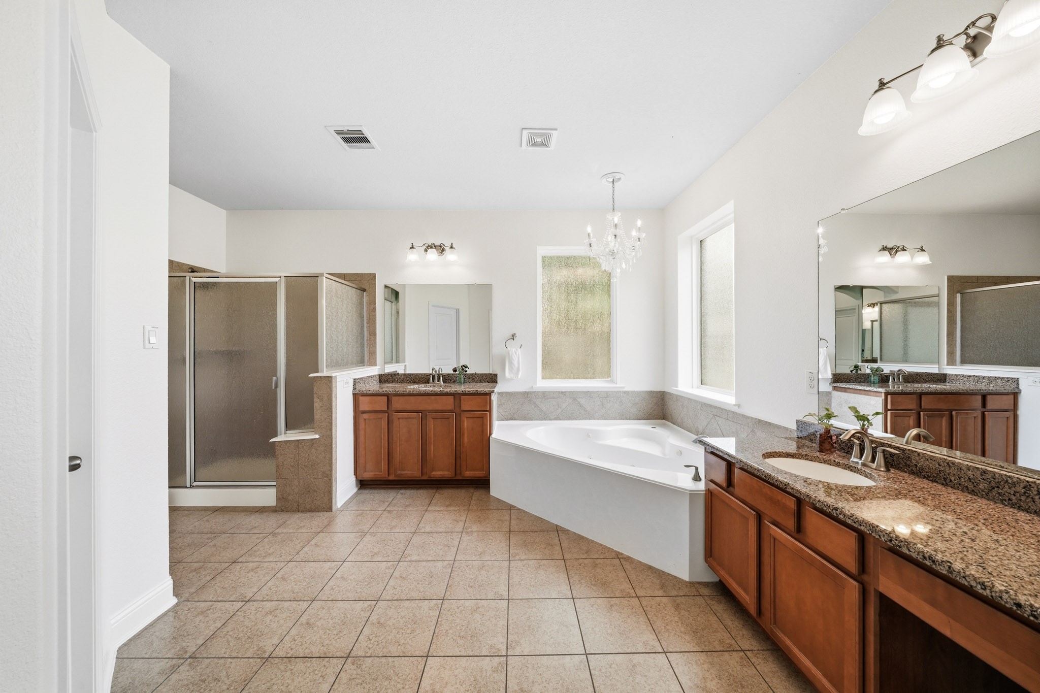 17610 Strackfield Lane Tomball, TX 77377 - Photo 24 of 50 Retreat to a beautifully appointed primary bath where dual sinks, granite counters, a makeup vanity, and elegant tile flooring create a refined space for daily routines.