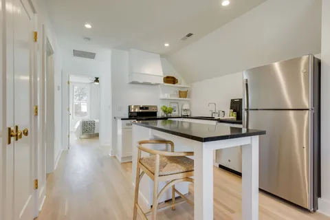 a kitchen with granite countertop a refrigerator a stove a sink and a dining table with wooden floor