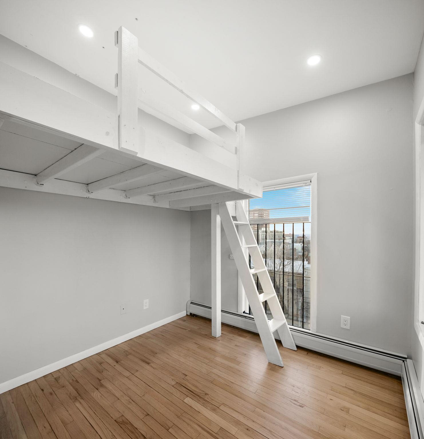 431 7th Street, Unit 2B Union City, NJ 07087 - Photo 9 of 16 a view of an empty room with wooden floor stairs