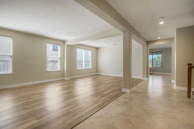 a view of an empty room with window and wooden floor