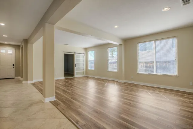 an empty room with wooden floor and windows