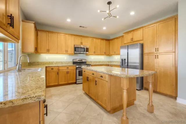 a kitchen with stainless steel appliances granite countertop a stove refrigerator sink and cabinets