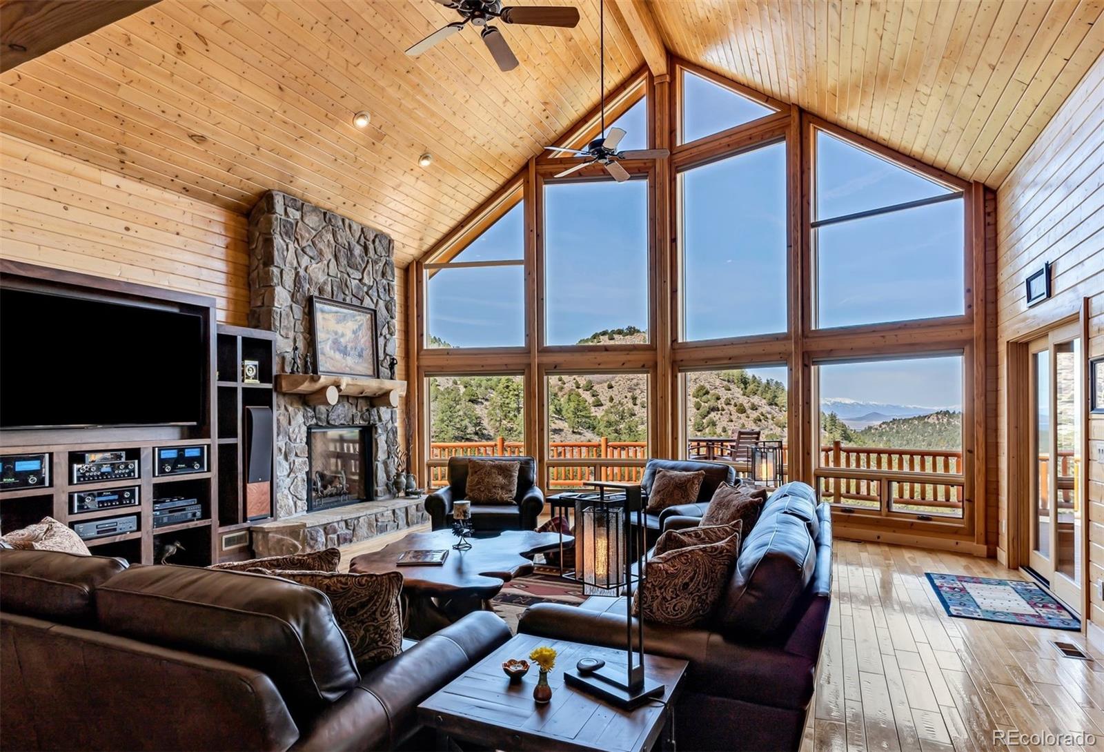 400 Ridge Road Westcliffe, CO 81252 - Photo 3 of 37 a living room with furniture a flat screen tv and a floor to ceiling window