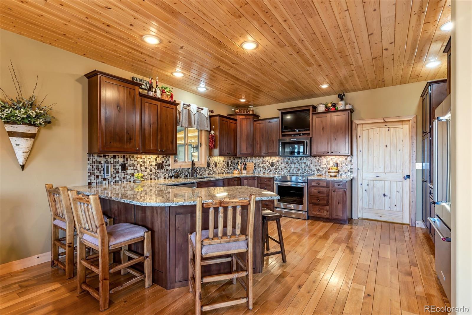 400 Ridge Road Westcliffe, CO 81252 - Photo 9 of 37 a kitchen with stainless steel appliances kitchen island granite countertop a table chairs sink and cabinets