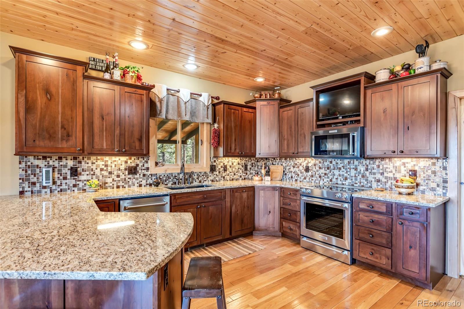 400 Ridge Road Westcliffe, CO 81252 - Photo 10 of 37 a kitchen with kitchen island granite countertop wooden cabinets and a stove top oven