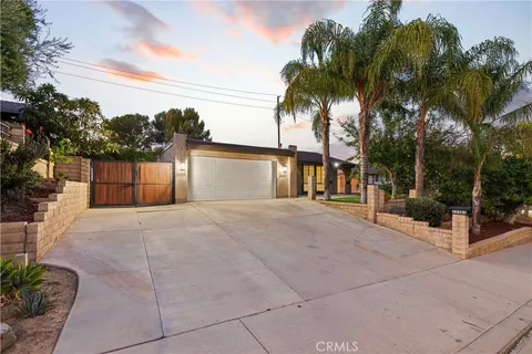 a view of a house with a yard and coconut trees