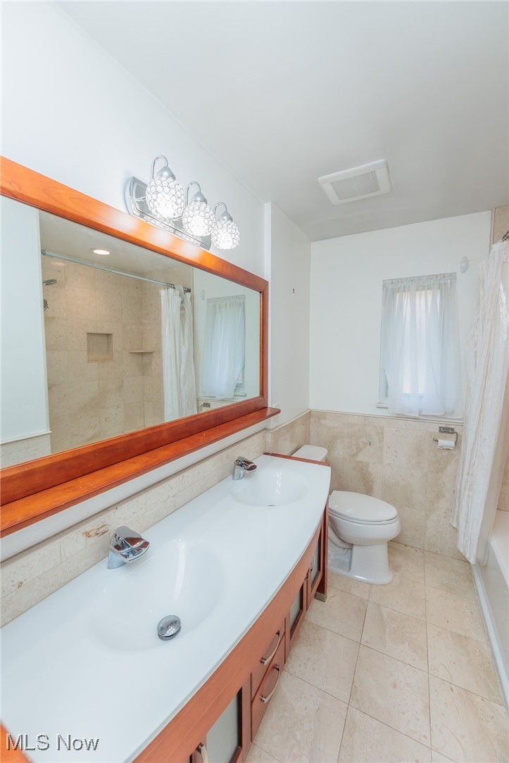 5445 Hauserman Road Cleveland, OH 44130 - Photo 23 of 45 Full bathroom featuring shower / tub combo with curtain, vanity, tile patterned floors, tile walls, and toilet