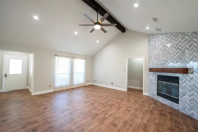 an empty room with wooden floor fireplace and windows