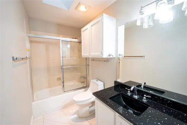 a bathroom with a granite countertop sink a toilet and shower
