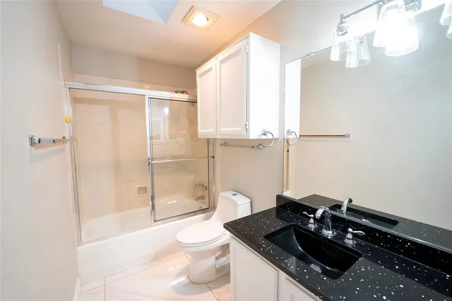 a bathroom with a granite countertop sink a toilet and shower