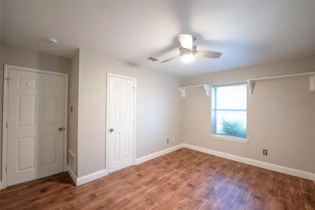 an empty room with wooden floor cabinet and windows