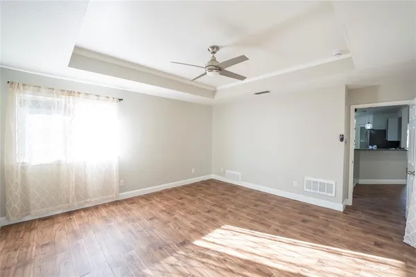 an empty room with wooden floor ceiling fan and windows